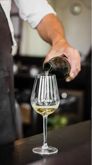 Vigneron versant du vin blanc dans un verre